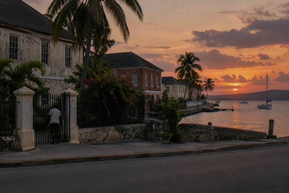 A small coastal town waterfront at dusk with low buildings and a darkening sky over the sea