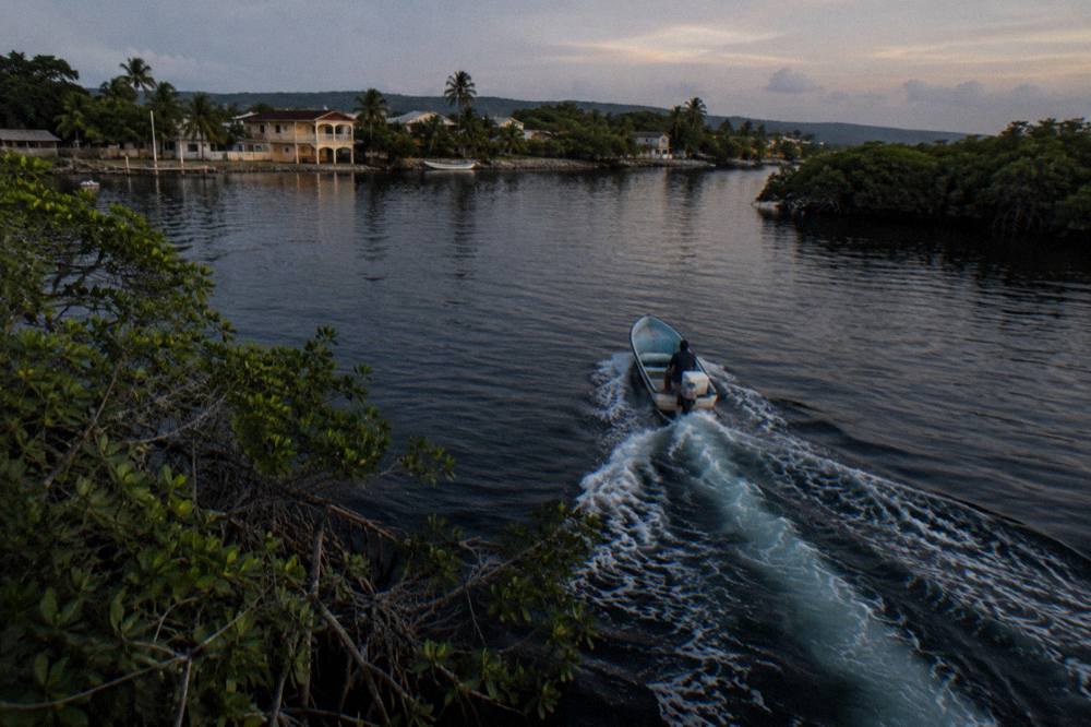 A boat wake glowing pale blue across dark water at night
