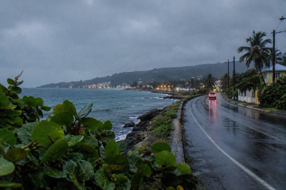 A coastal highway curving along a dark shoreline with distant town lights