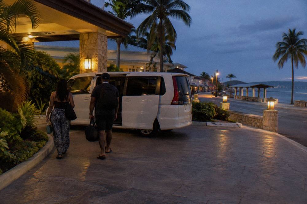 A lit swimming pool and palm trees at a resort hotel at dusk