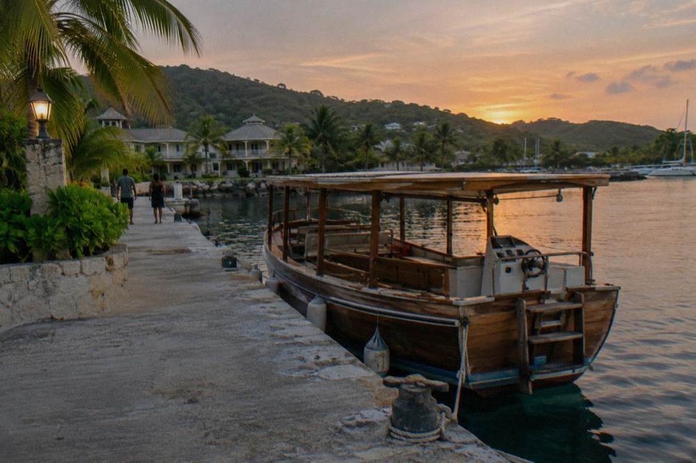 Towel water shoes and dark swimwear folded on a bench beside a dock at dusk