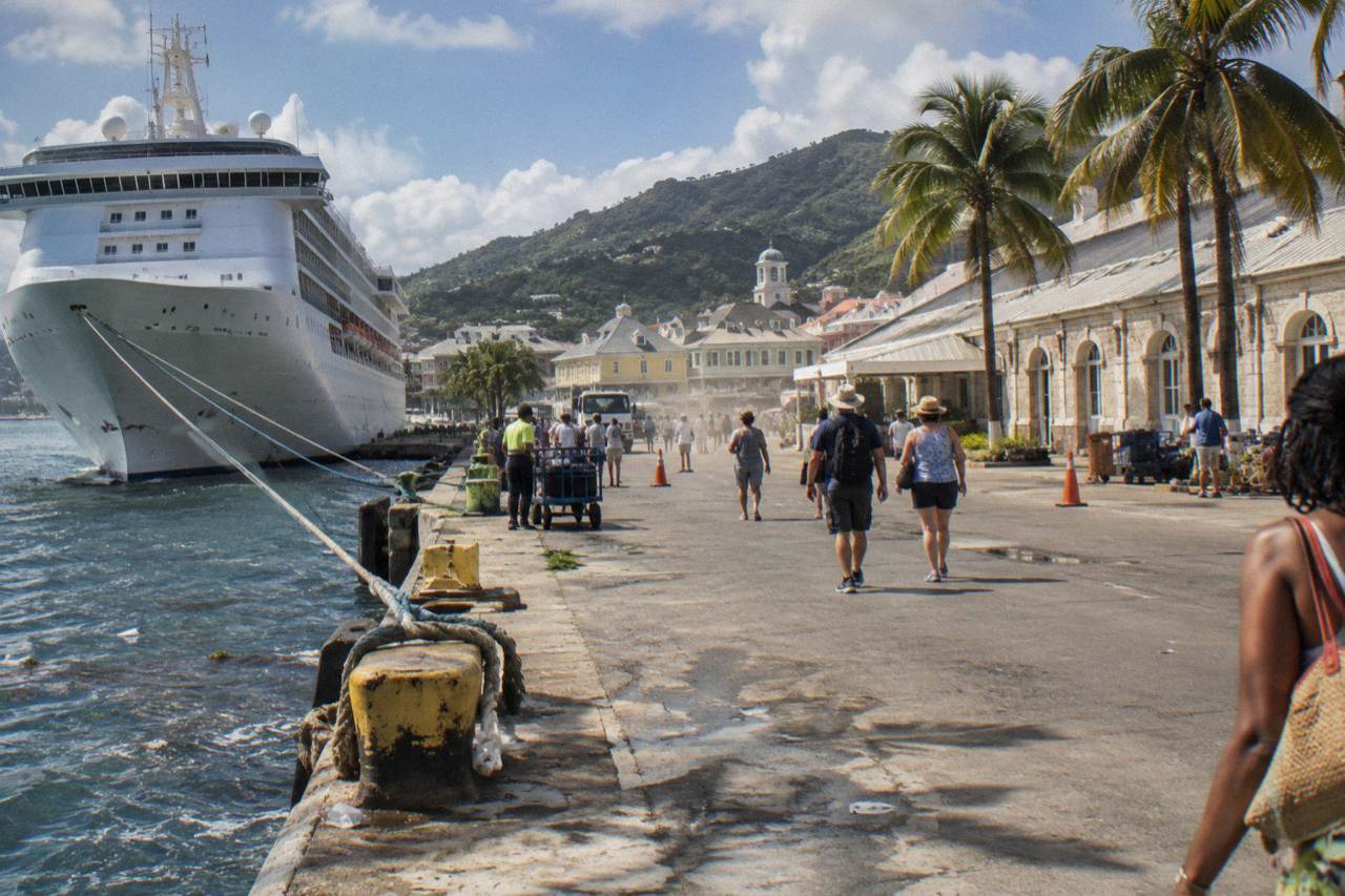 Cruise ship docked at a Caribbean port town with Georgian buildings along the waterfront