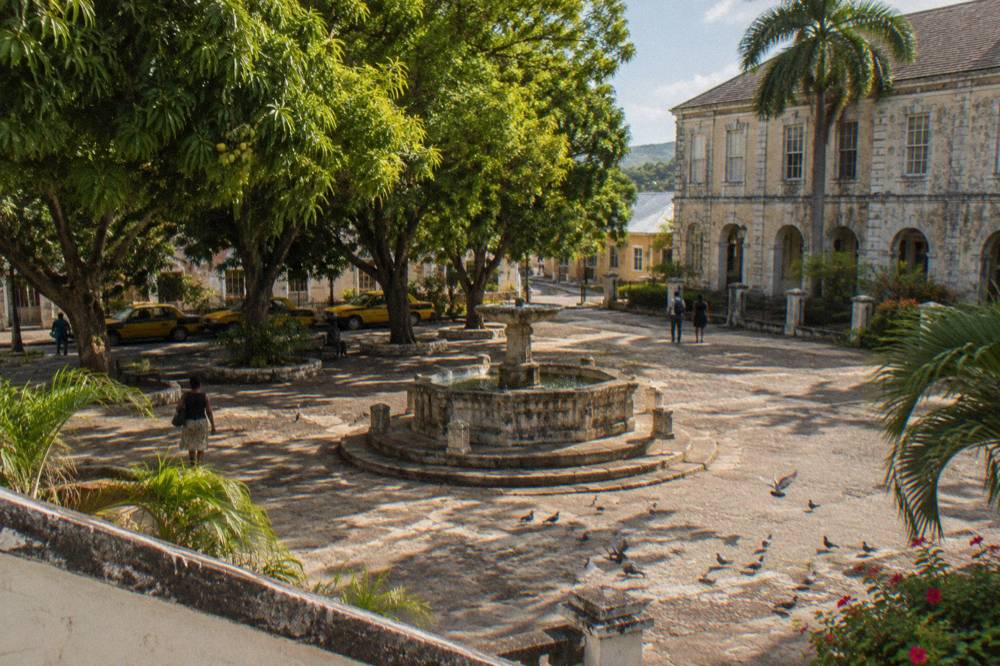 Water Square in Falmouth with its stone fountain and parked taxis under tall trees