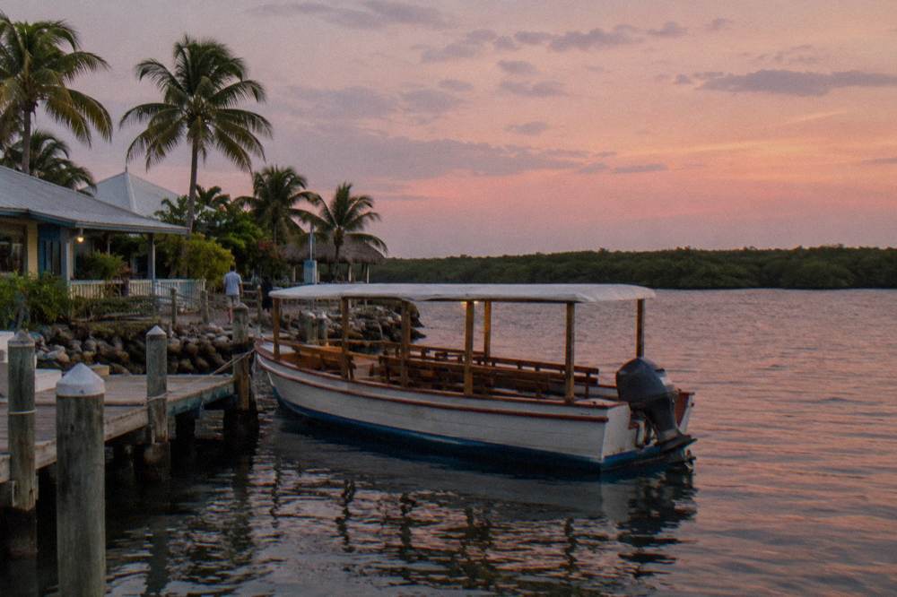 A wooden tour boat at a marina dock on a calm brackish lagoon at dusk
