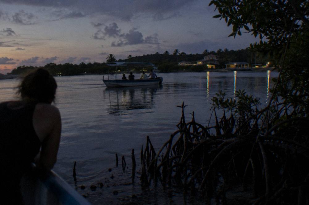 A flat bottomed boat drifting on dark still lagoon water at nightfall