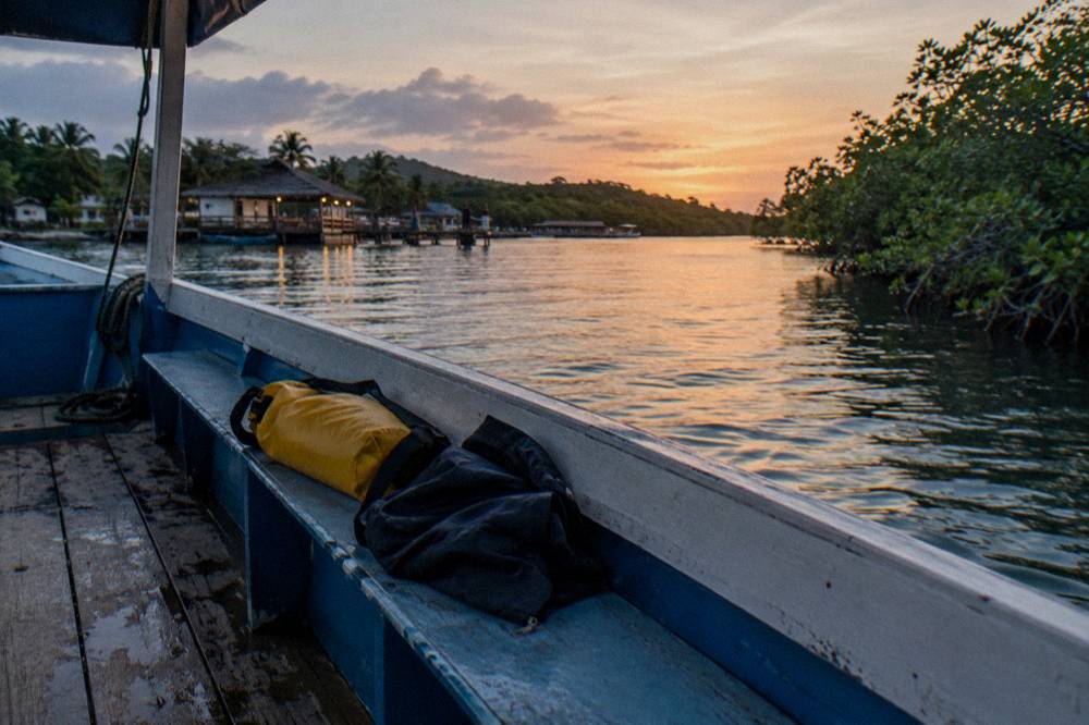 A folded towel and dry bag resting on a boat bench beside a jacket