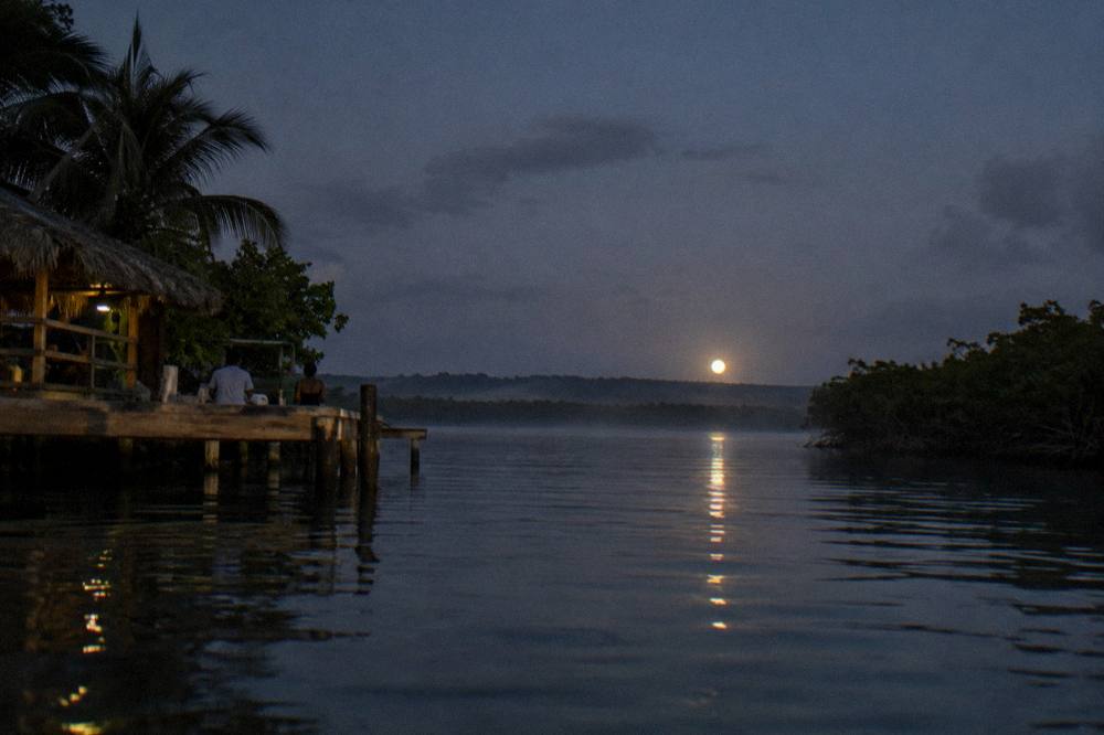 Night sky over calm lagoon water with the moon low on the horizon