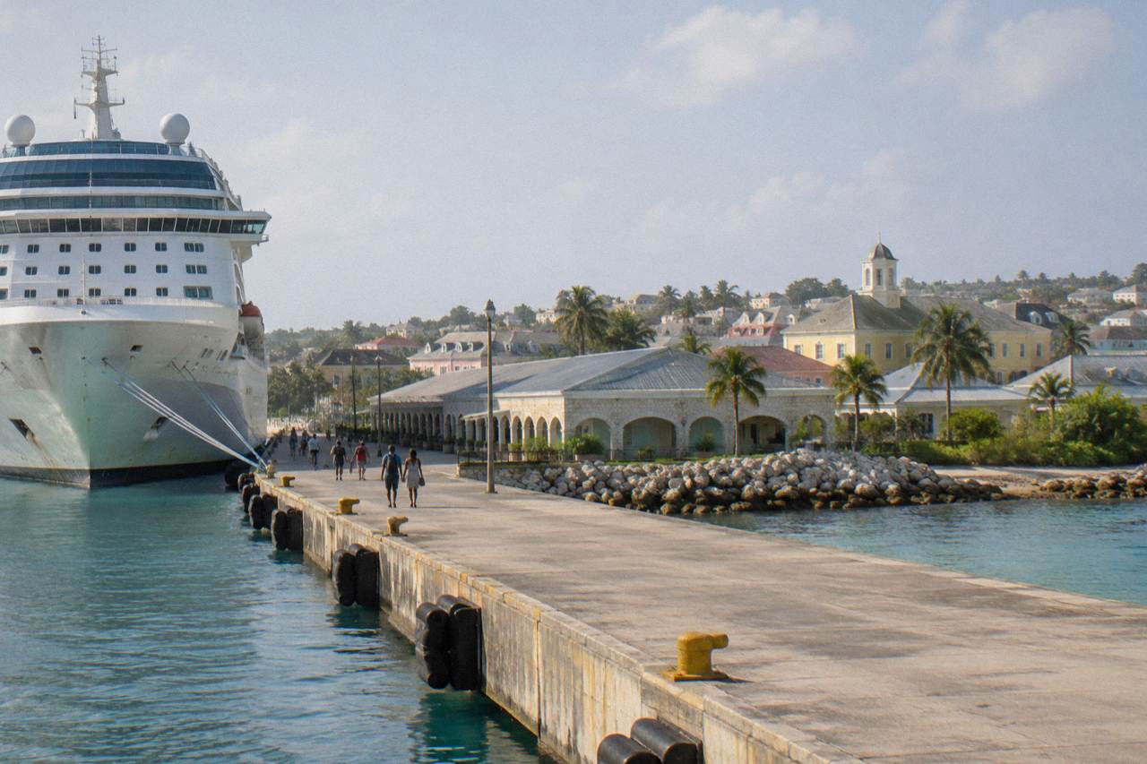 Cruise ship docked at a Caribbean port town with Georgian buildings along the waterfront