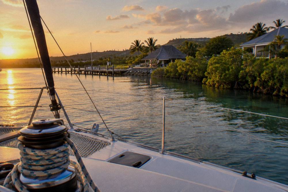 Catamaran deck at sunset with drinks on a table and calm sea beyond