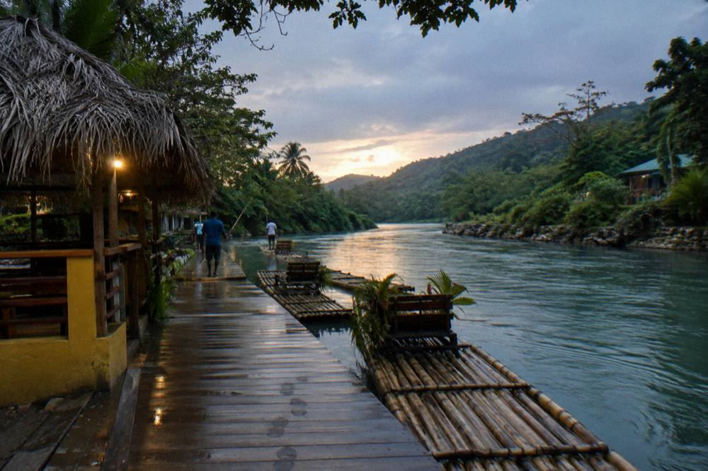 A folded towel and dark swimwear on a bench beside a river dock at dusk