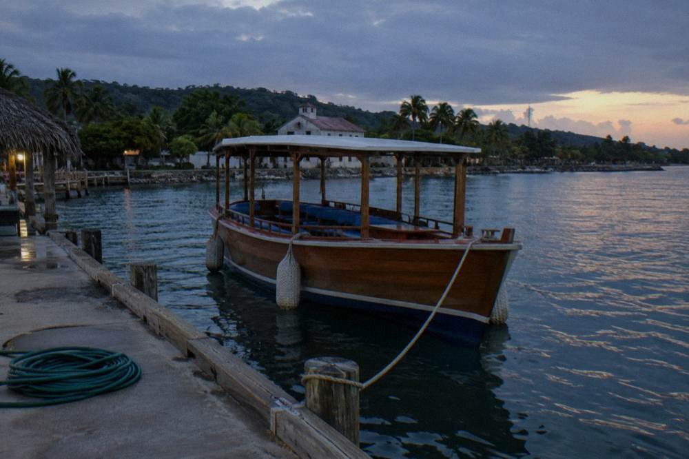 A wooden tour boat at a marina dock under a darkening sky