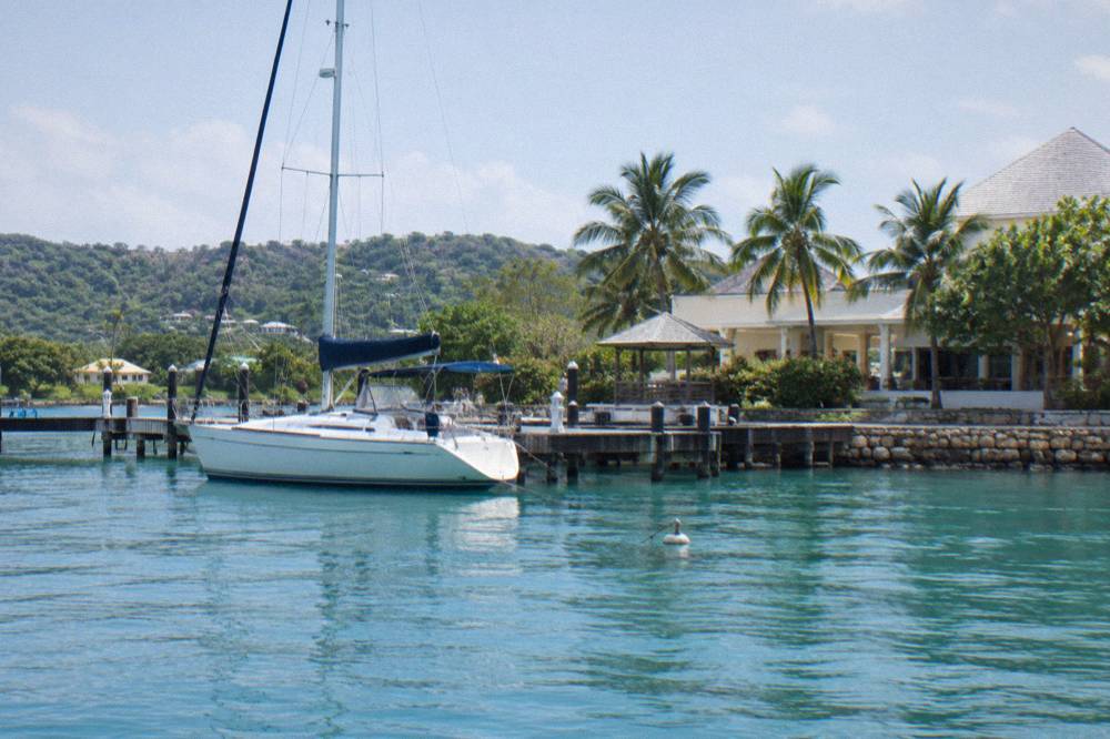 A yacht anchored on calm turquoise lagoon water near a wooden marina dock