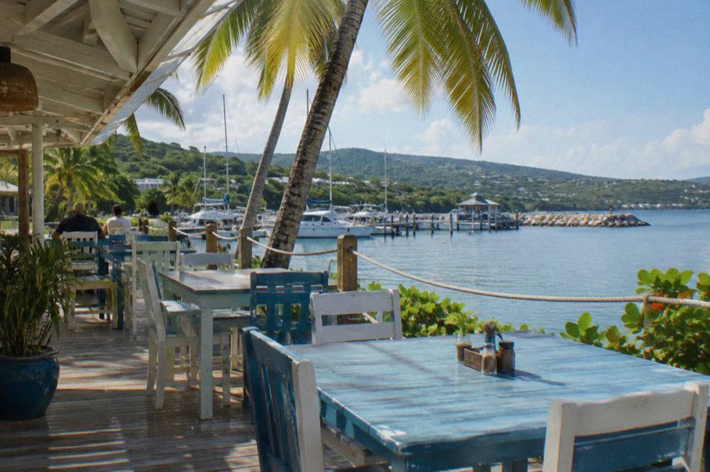 An outdoor restaurant terrace overlooking a calm lagoon and palm trees
