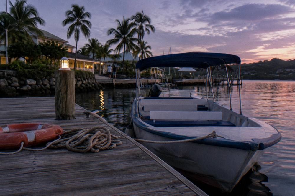 A small open tour boat at a wooden dock at dusk with dark water beyond
