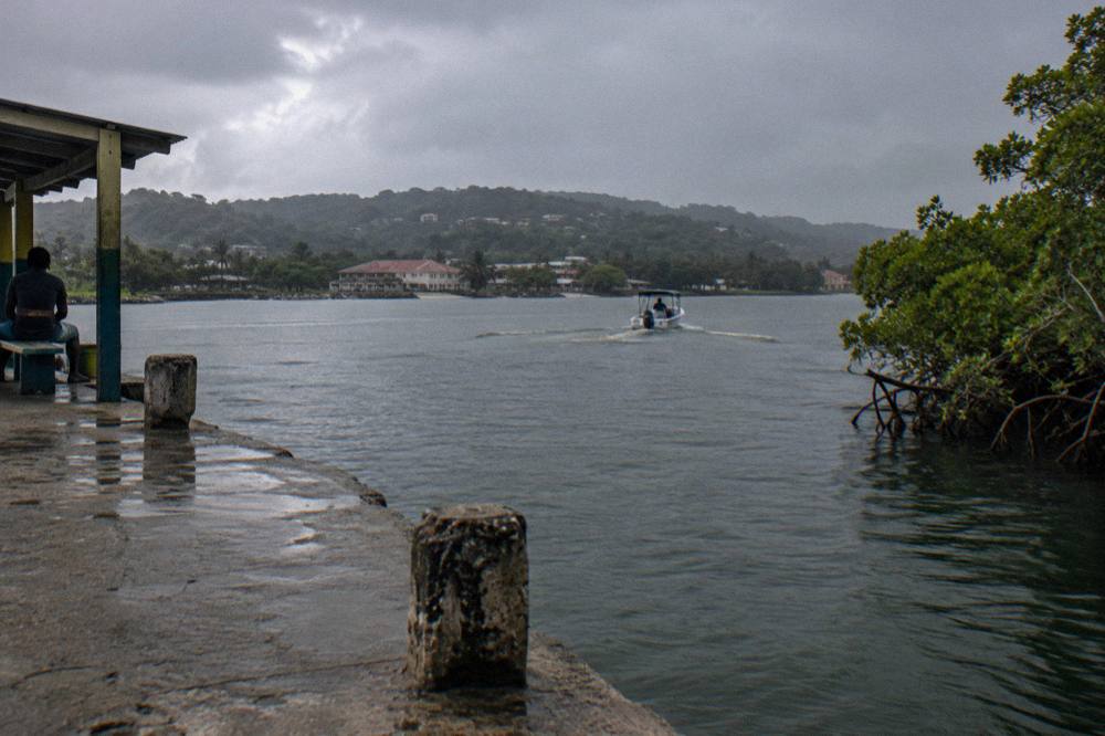 A darkening lagoon surface with faint ripples spreading from a boat wake