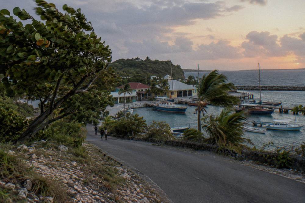 Coastal road curving toward a small marina with boats at dusk in Jamaica