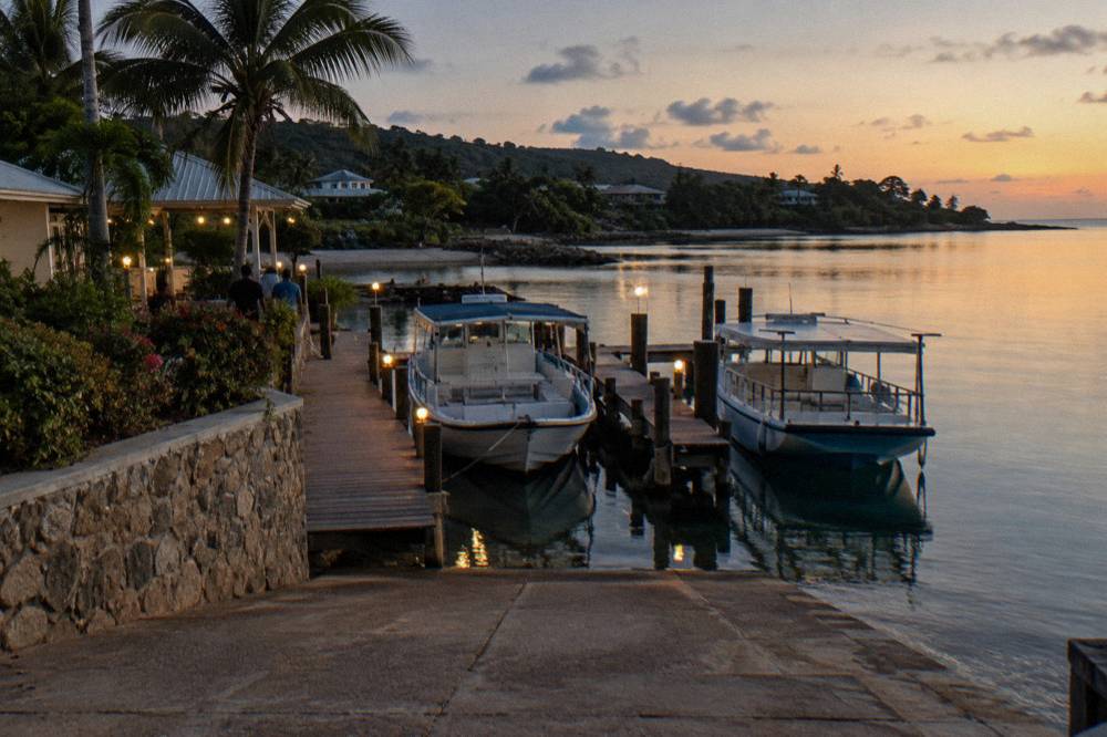 Two moored tour boats at a wooden marina dock under warm lights before a night cruise