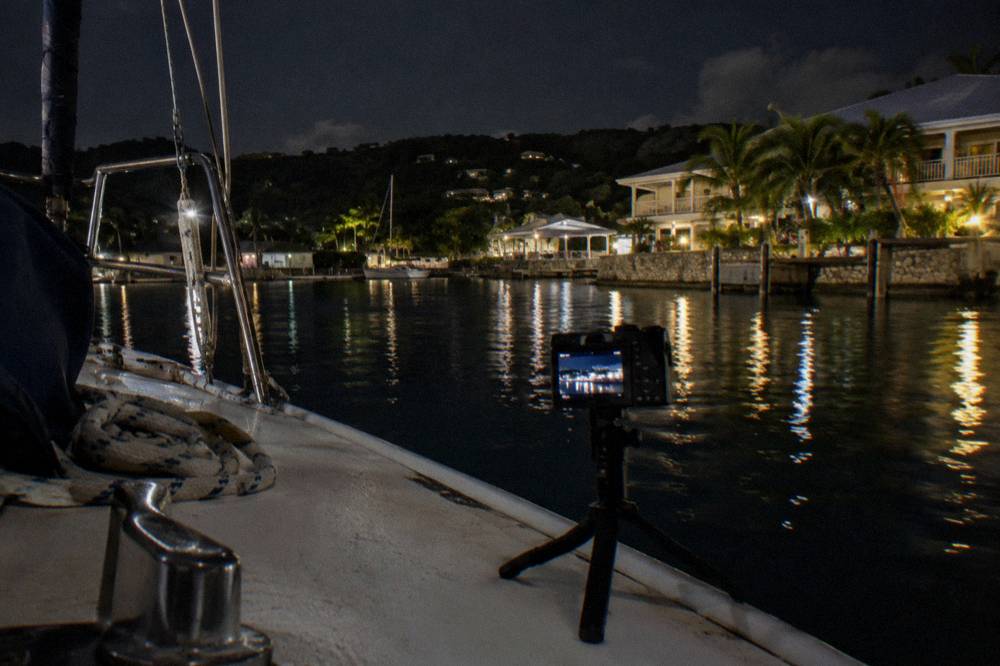 A camera on a small tripod set up on the deck of a boat at night