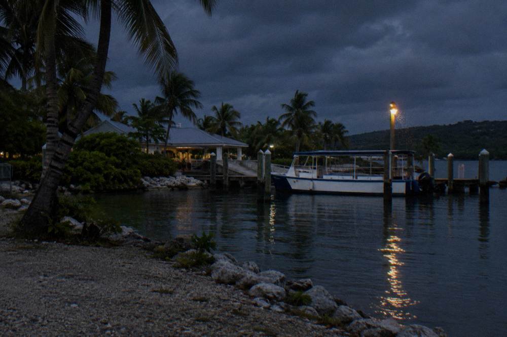 A small tour boat at a marina dock at dusk with dark sky above the water