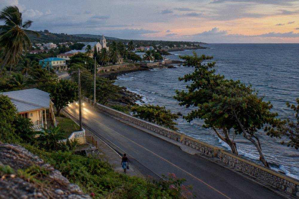 A coastal highway curve beside dark sea water in early evening