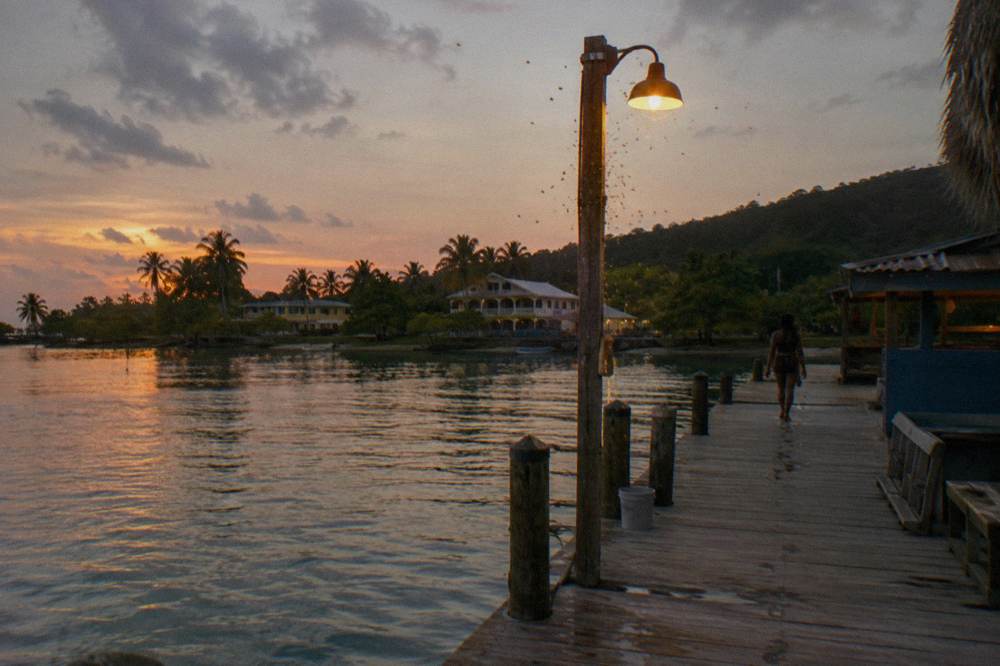 Small daypack with a rolled towel and a dry pouch on a dock bench at nightfall