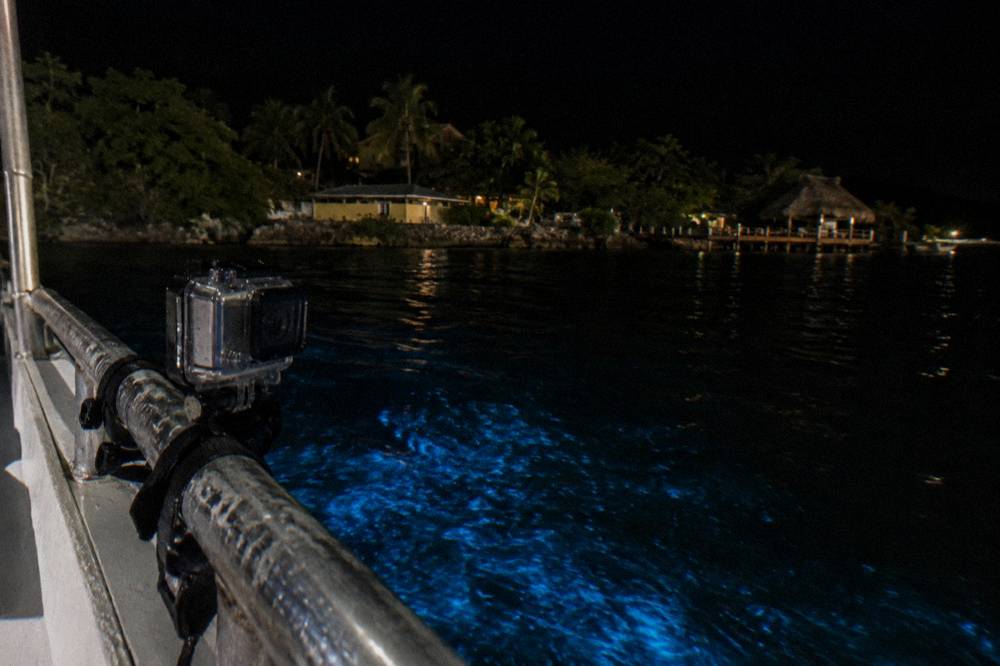 Camera in a waterproof case on a boat rail above dark water