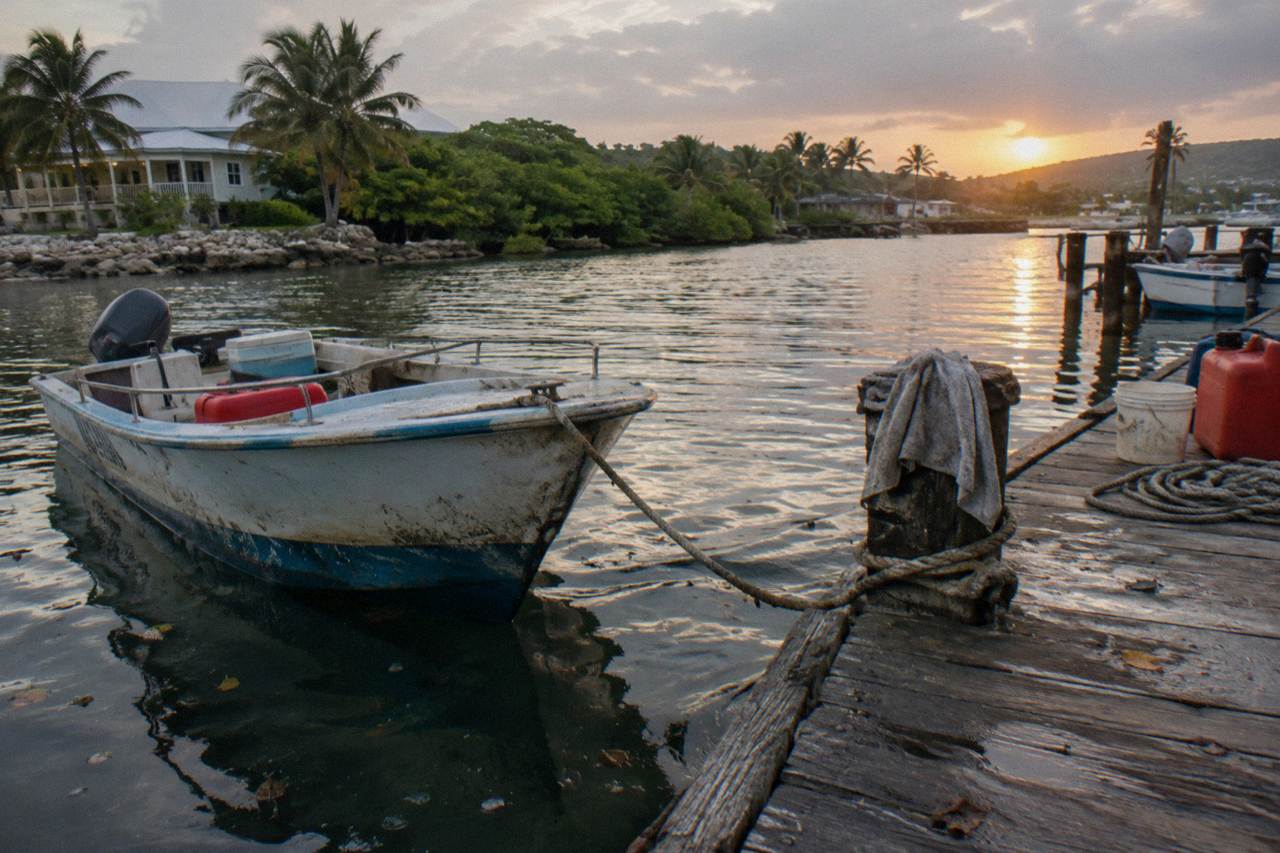 Wooden dock at a dark lagoon edge at dusk with a small tour boat tied up and still water