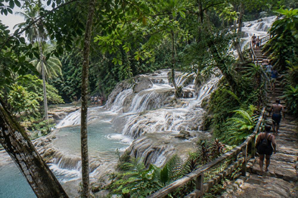 Terraced waterfall cascading through tropical forest with wooden stairs alongside