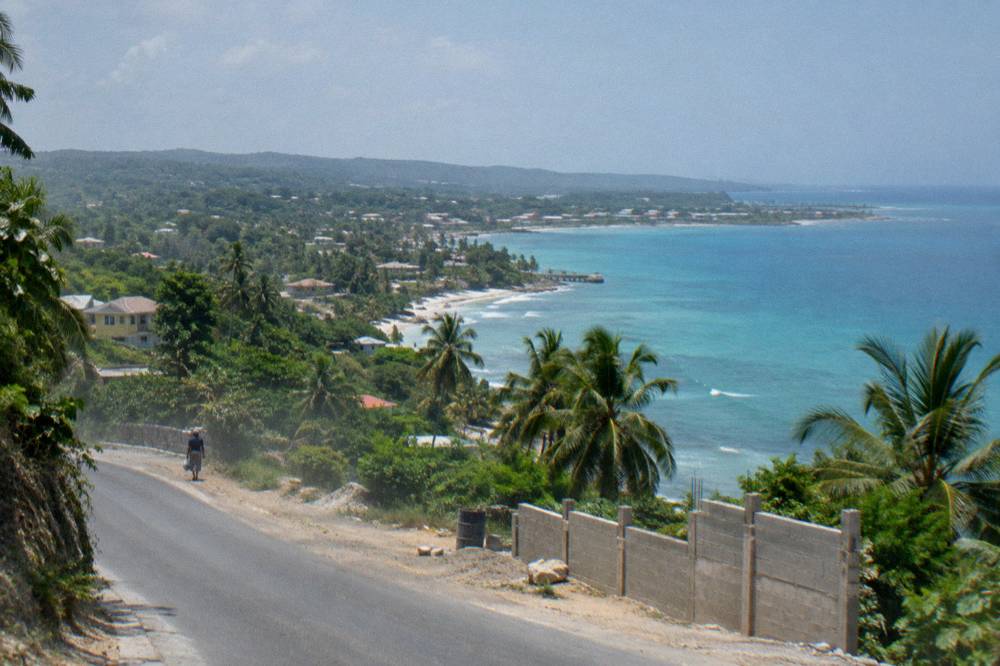 Coastal highway curving along a green hillside with the sea beyond