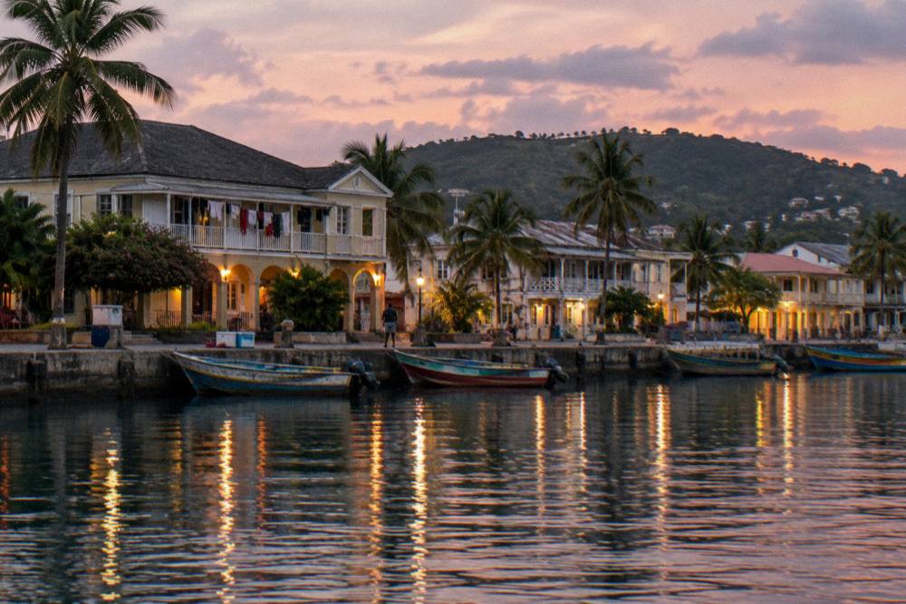 A harbor town at dusk with lit waterfront buildings and calm water